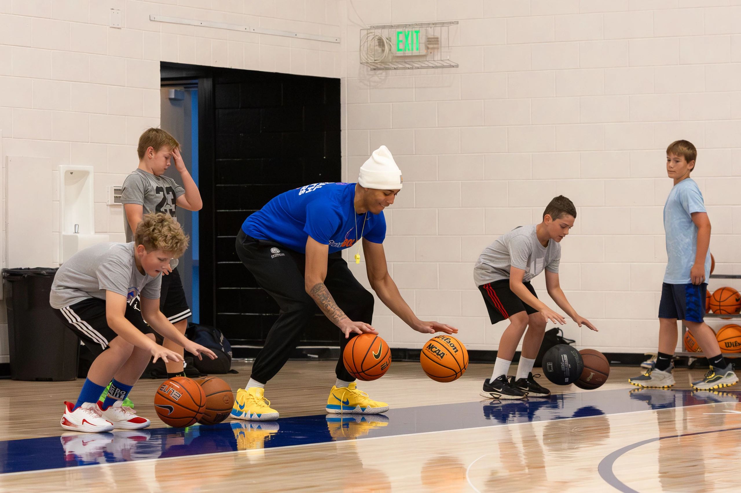 A college basketball coach leading a youth dribbling drill at a Top Tier camp